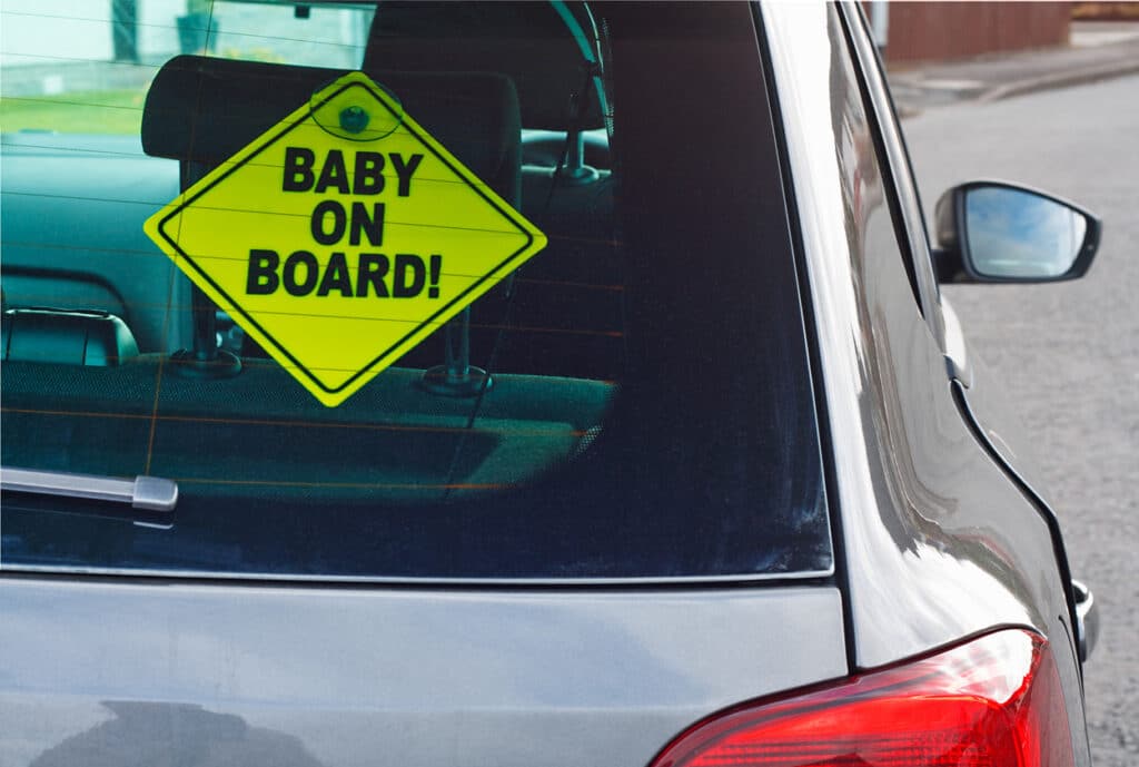 Baby on board warning sign in the back window of a car to advise cars behind of the presence of a toddler or infant.