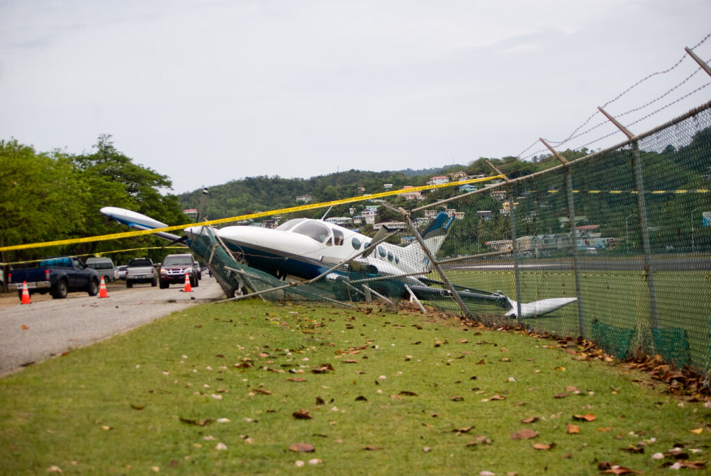 Small plane crashes through fence on highway in emergency landing.
