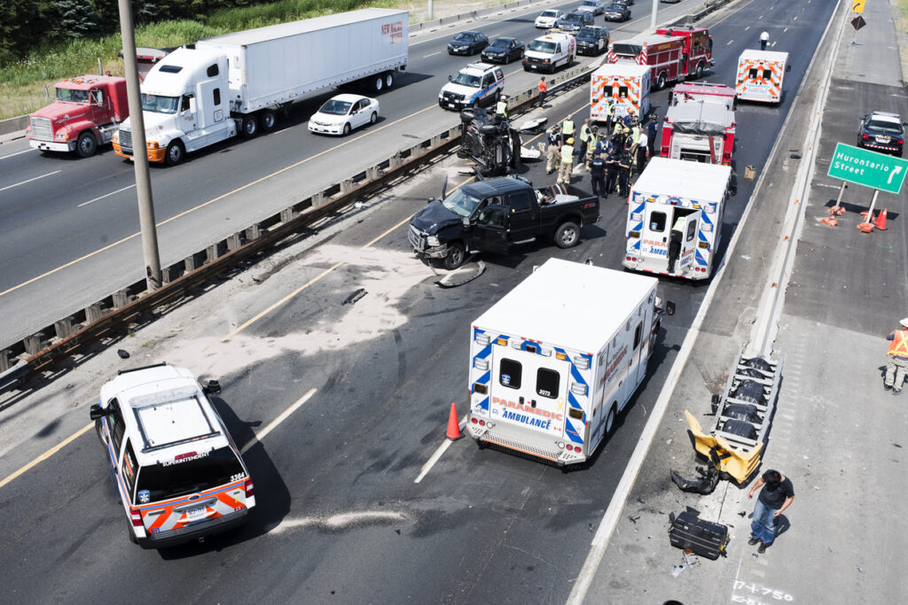 Fire department personnel, police officers, and paramedics respond to the scene of a collision on the highway.