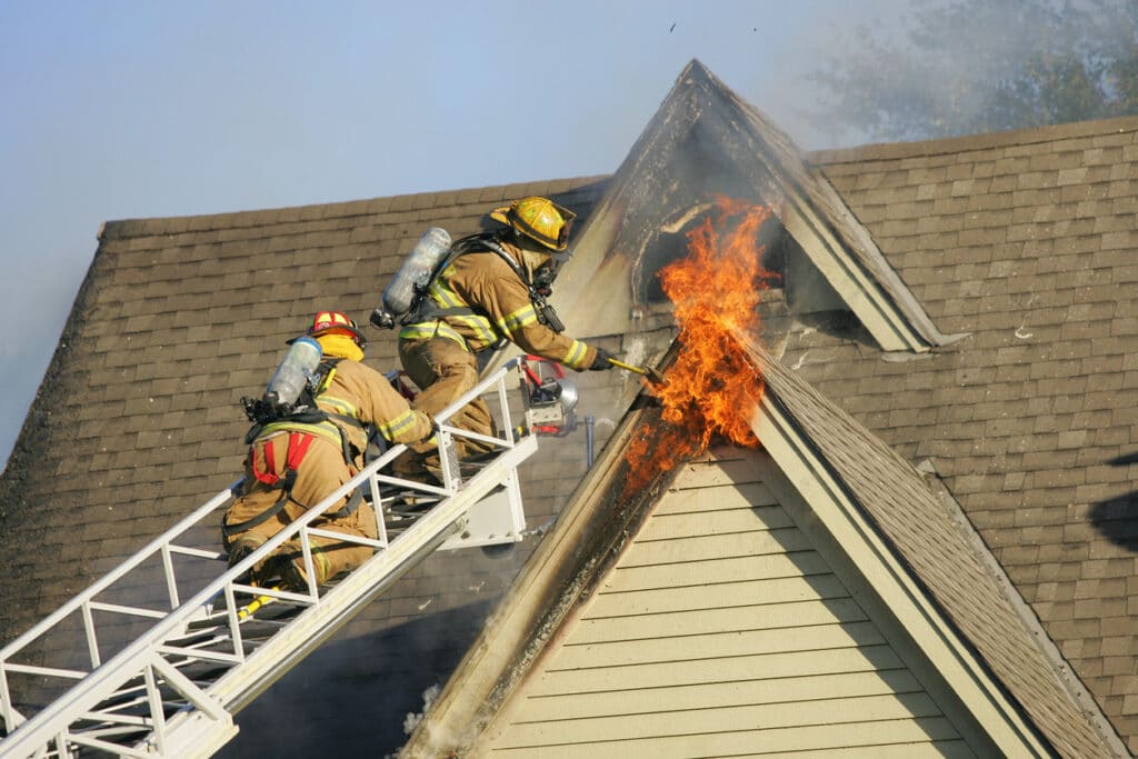 Two firemen working to put out a house fire.