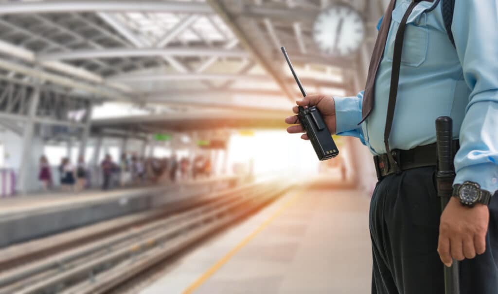 Professional security guard holding a walkie-talkie in the train station.