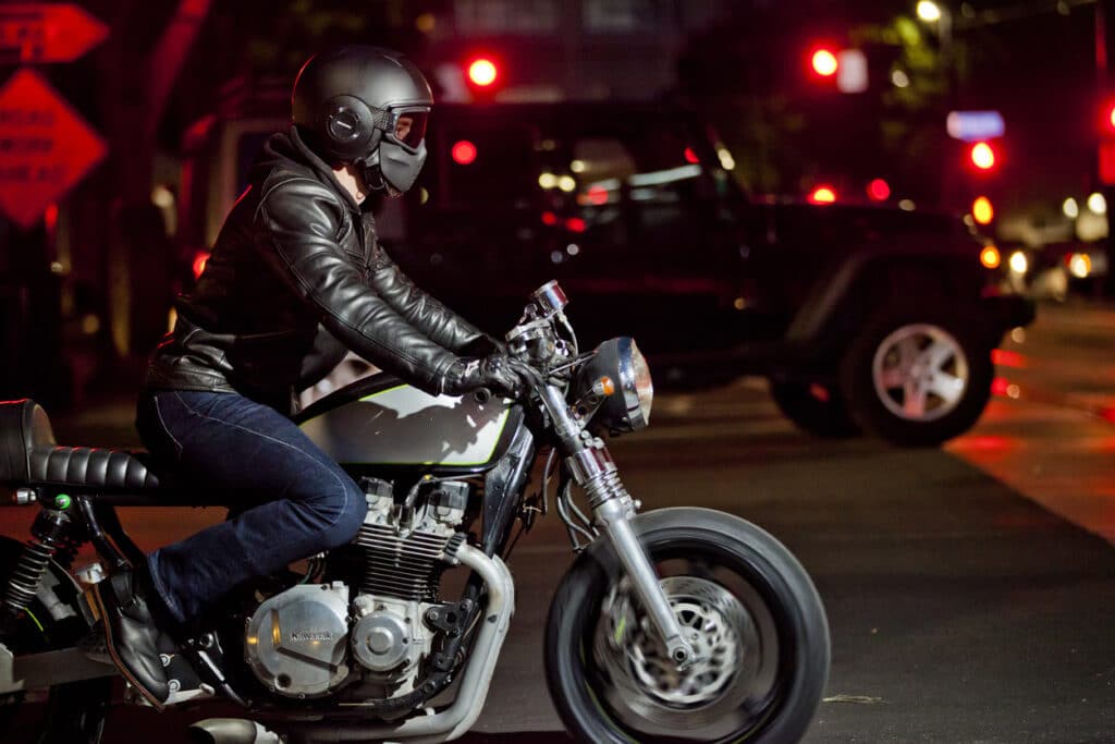 A man riding his motorcycle through the city at night.