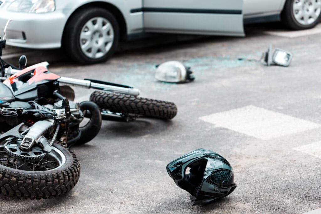 Overturned motorcycle and helmet on the street after collision with the car.