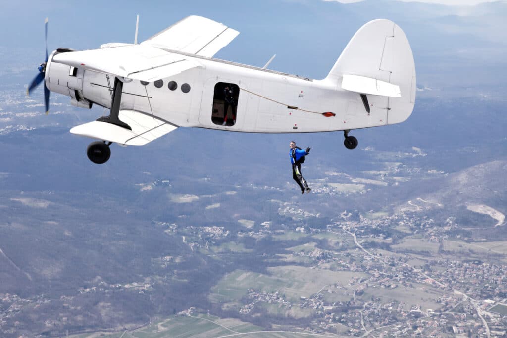 Parachuters are jumping from a plane to skydive.