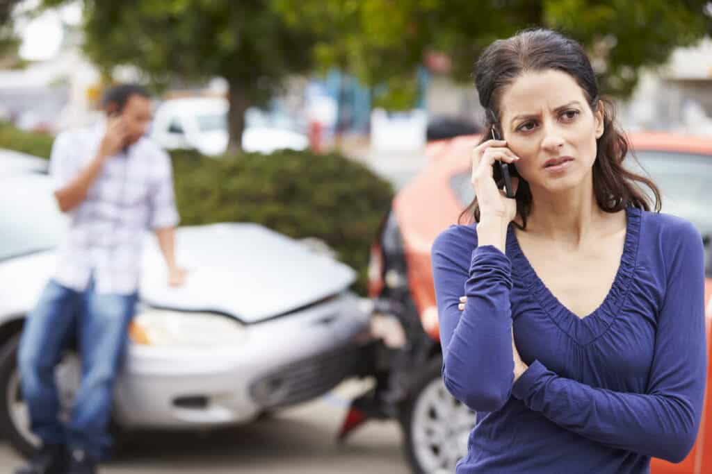 A woman making a phone call after a car accident.