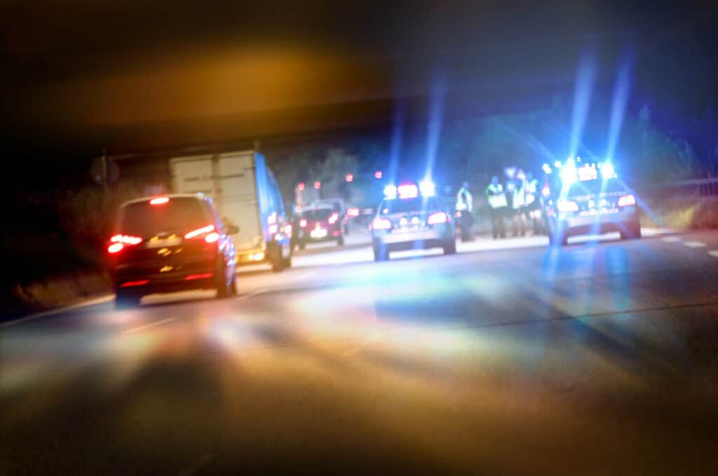 Police cars on highway at night blocking off an accident.